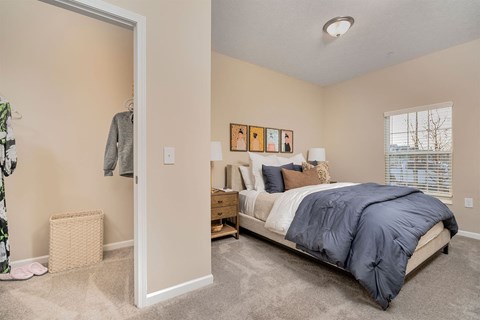 A bedroom with a bed, nightstand, and a wall hanging with pictures.