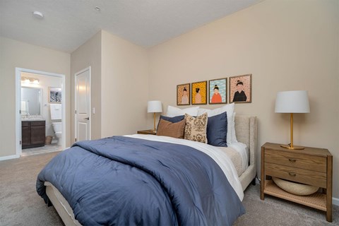 A bedroom with a bed, nightstand, and lamp.