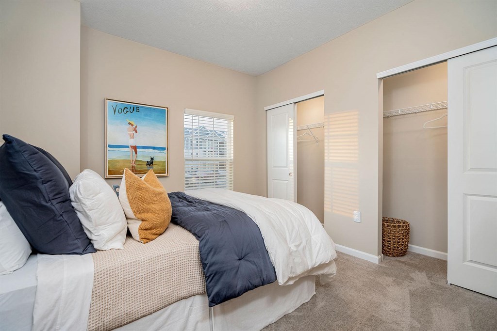 A bedroom with a bed, a poster, and a wicker basket.