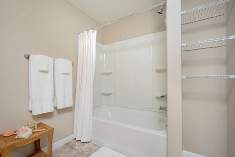A white bathtub with a shower curtain and towels hanging on the wall.