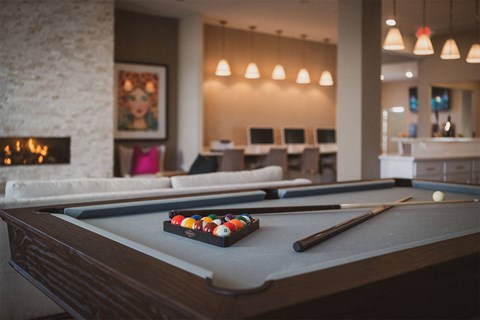A pool table with a set of balls and a cue stick on it.
