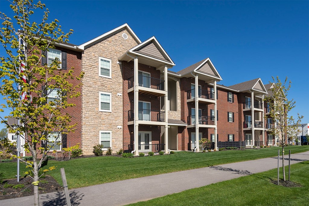 A large brick apartment building with a walkway in front.