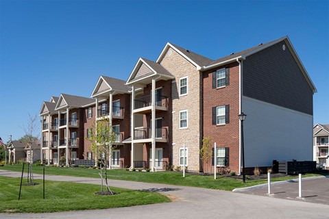 A large apartment complex with multiple balconies and a parking lot in front.