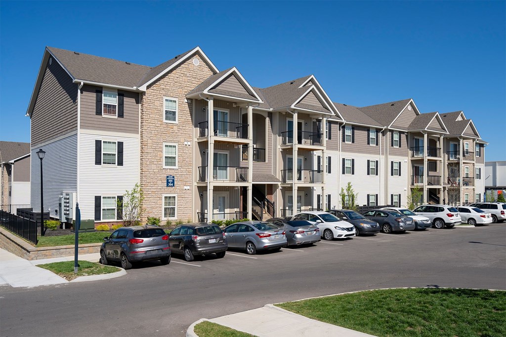 A row of cars parked in front of apartment buildings.