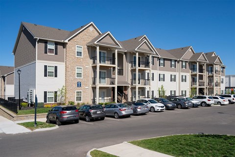 A row of cars parked in front of apartment buildings.