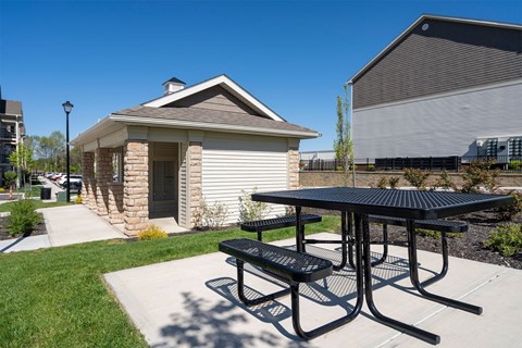 A small building with a black picnic table in front of it.