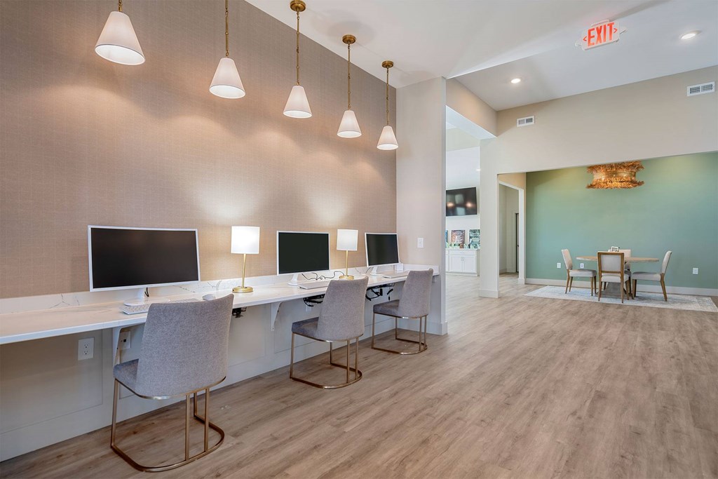 A room with a long table and chairs with a green wall and a red exit sign.