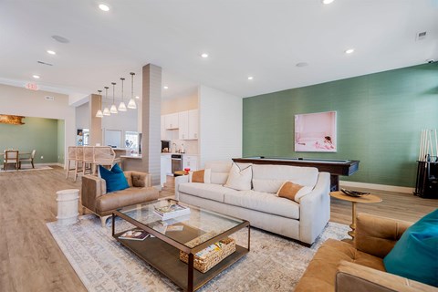 A living room with a white couch, brown armchair, and a glass coffee table.