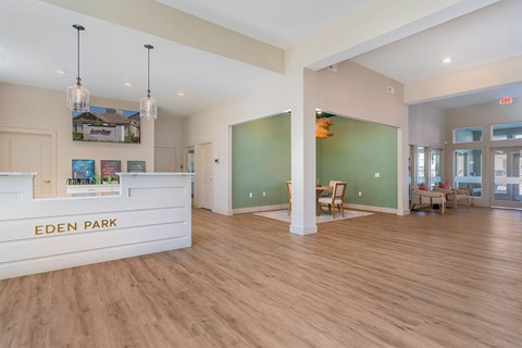 A reception area with a white reception desk that says Eden Park.