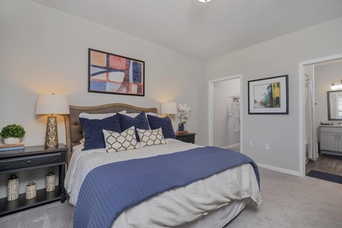 A bedroom with a large bed and a painting on the wall.