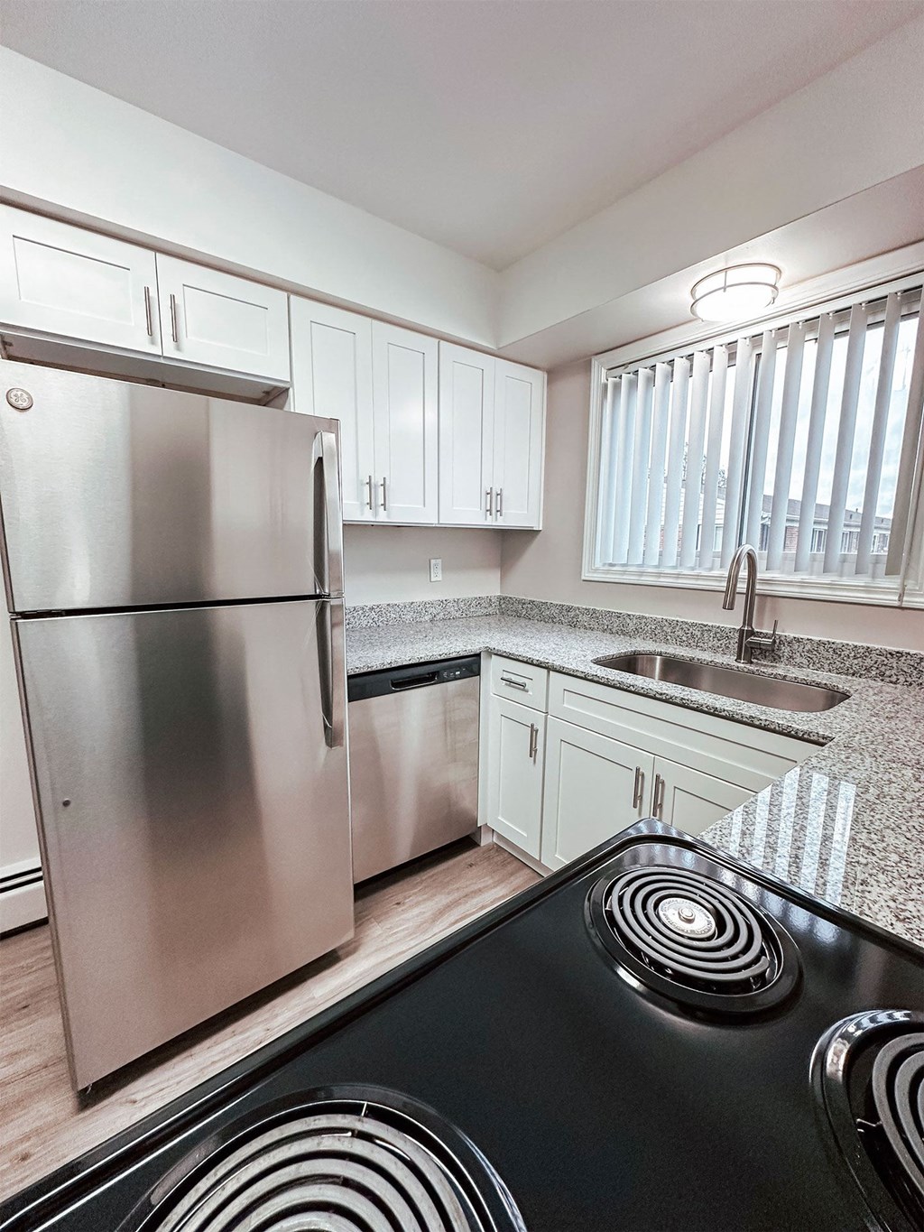 A modern kitchen with a stainless steel refrigerator and black stove top.