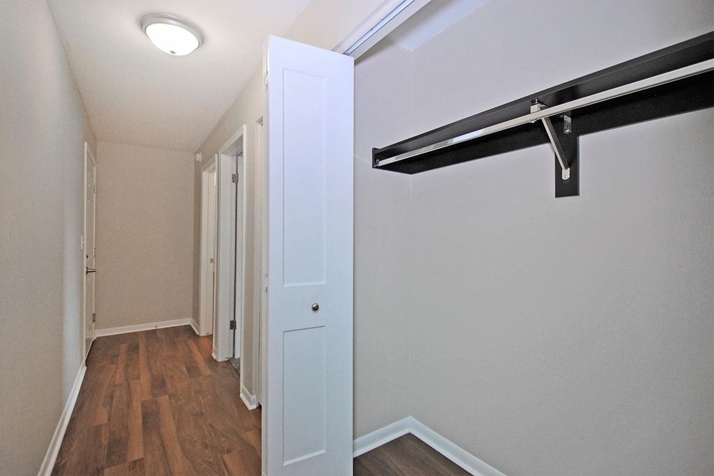 a bedroom with a closet and a white door and a hallway with wood floors