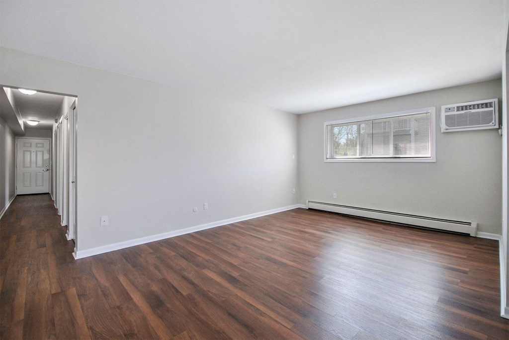an empty living room with wood floors and a window