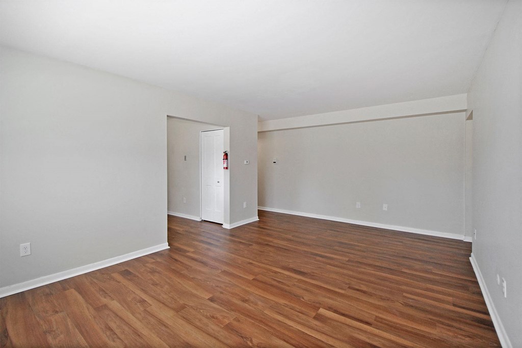 the spacious living room with wood flooring and white walls