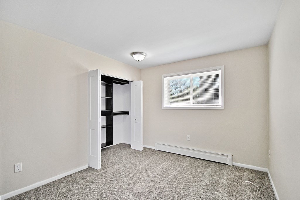 an empty room with white walls and a window and a closet