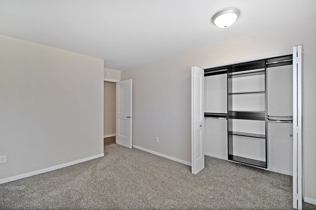 a bedroom with white walls and a closet with a mirrored door
