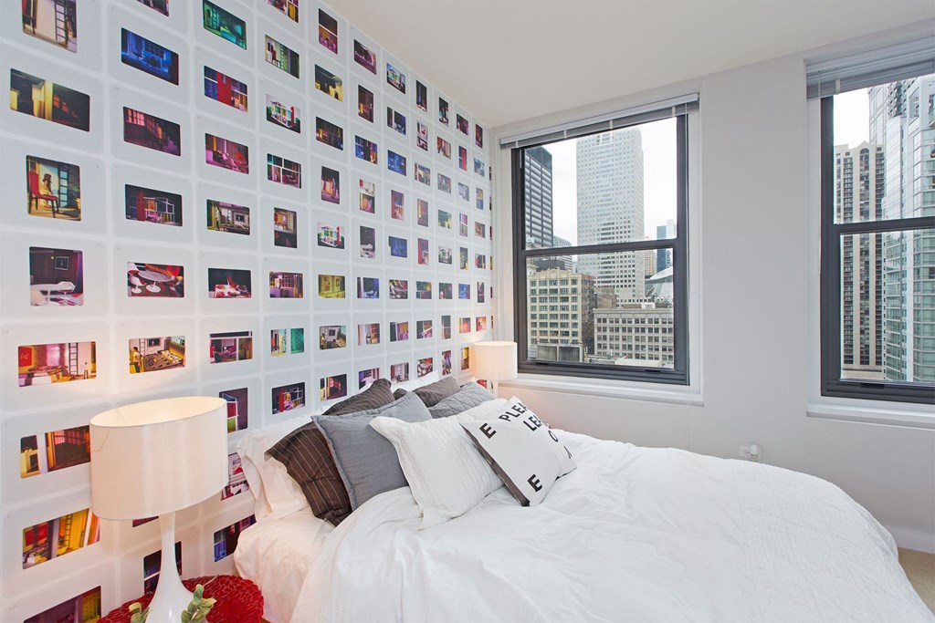 a bedroom with a bed and a wall covered in photos