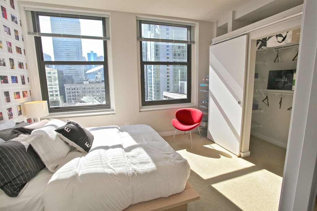 a bedroom with a bed and a closet and three windows