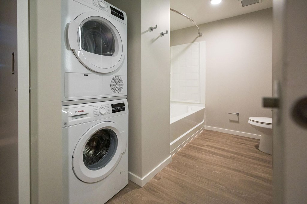 a washer and dryer in a laundry room with a tub and a toilet