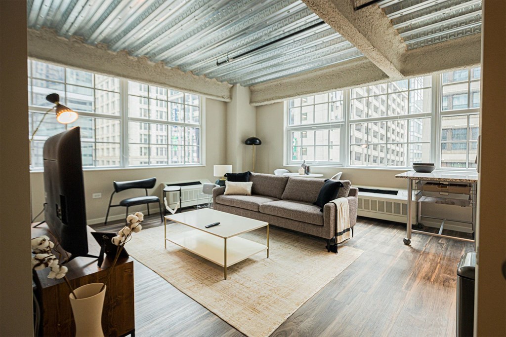 a living room with a couch and a coffee table and large windows