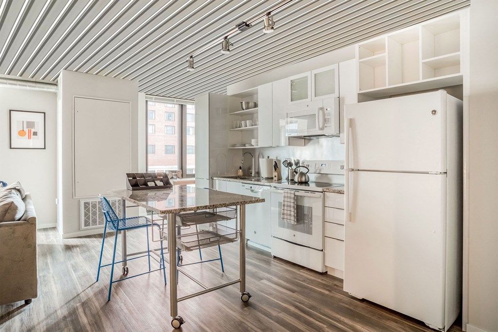 a kitchen with white appliances and a table with two stools