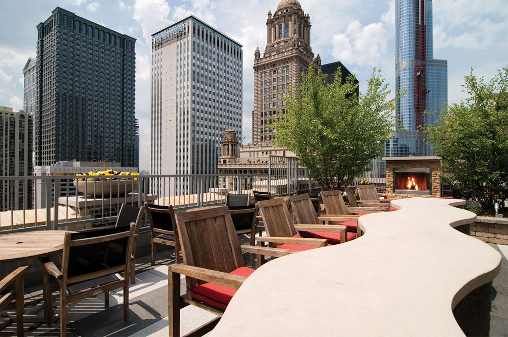 a rooftop patio with tables and chairs and a fire pit