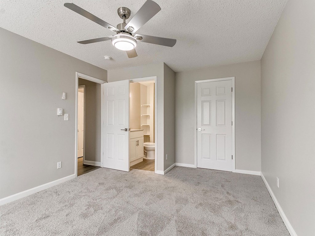 an empty living room with a ceiling fan and a closet