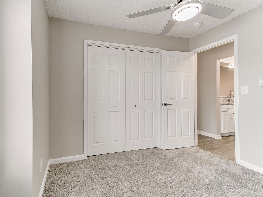 an empty bedroom with two closets and a ceiling fan