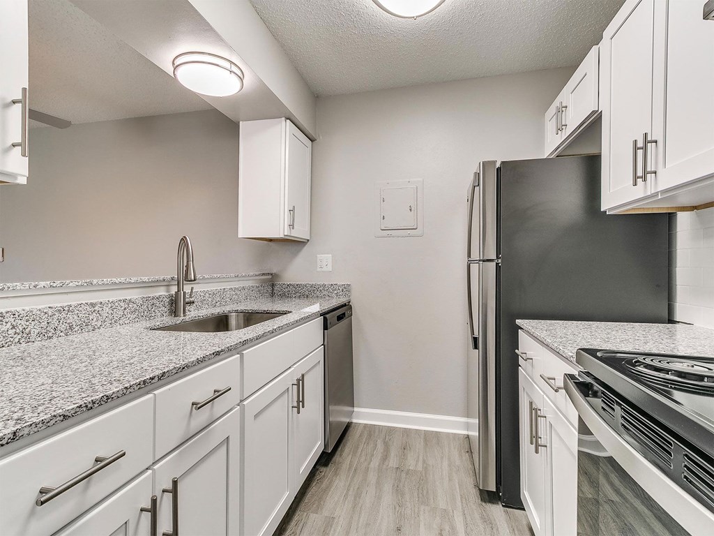 an empty kitchen with white cabinets and a stainless steel refrigerator