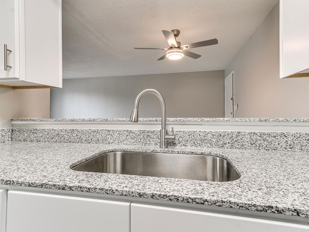 a kitchen with a sink and a ceiling fan