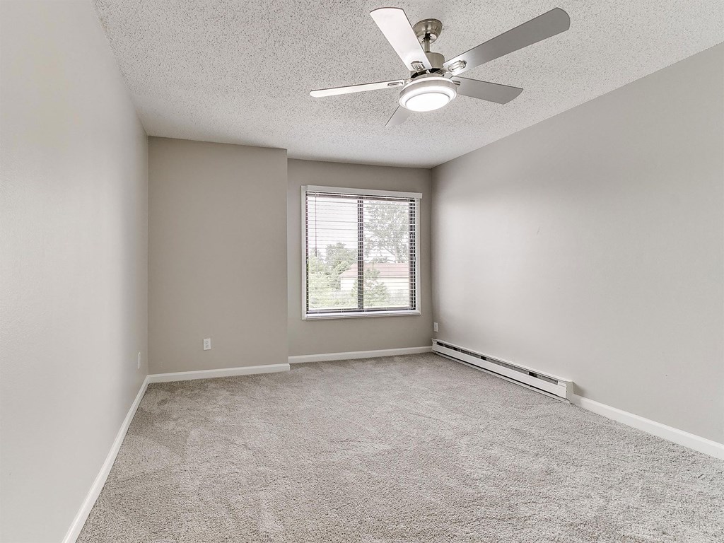 an empty living room with a ceiling fan and a window