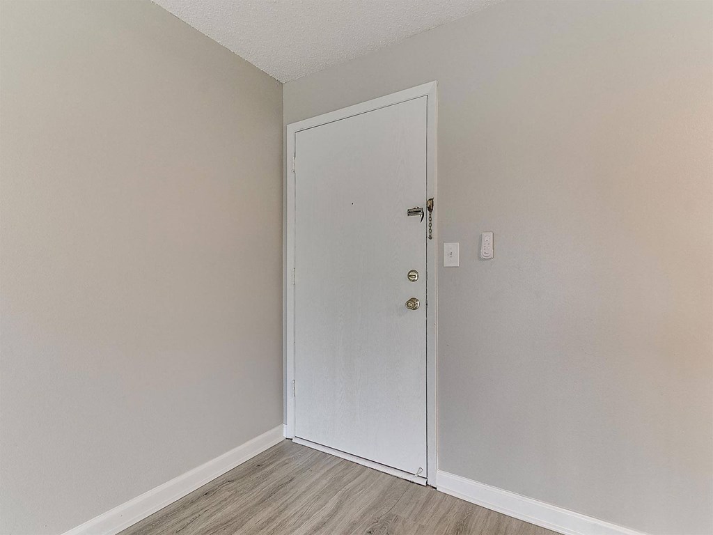a bedroom with a white door and a wooden floor