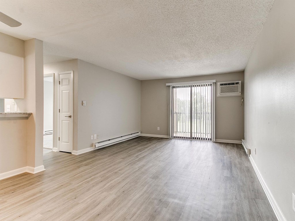 the living room and dining room of an empty apartment with wood flooring