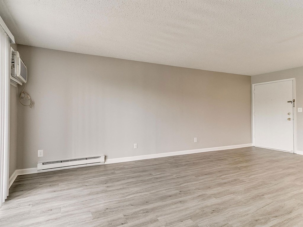 an empty living room with wood floors and white walls