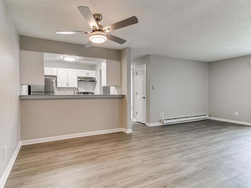 an empty living room and kitchen with a ceiling fan