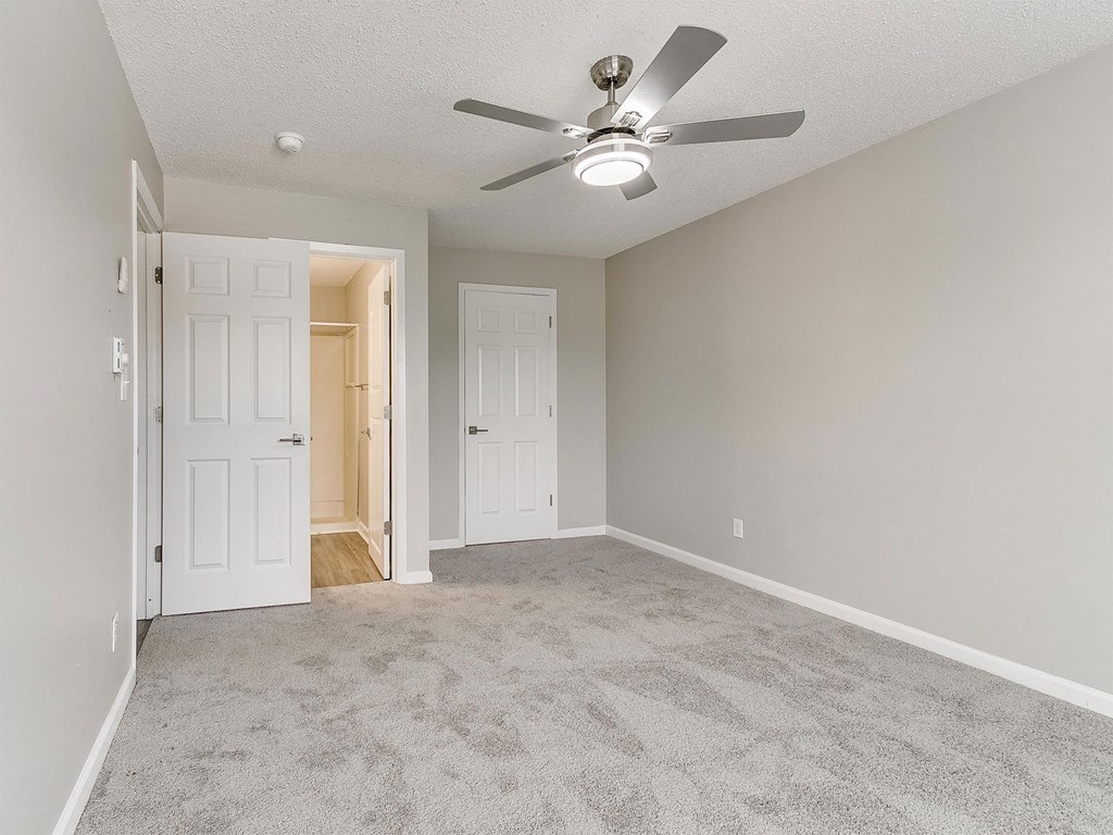 an empty living room with a ceiling fan