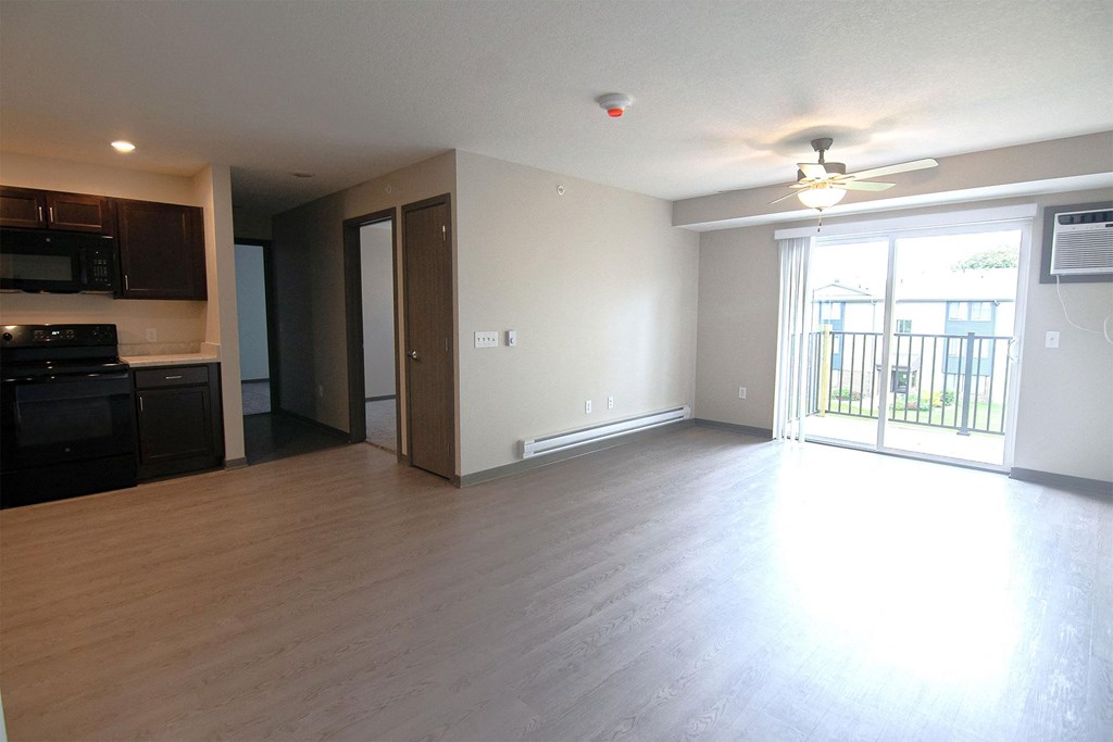 an empty living room with wood flooring and a balcony