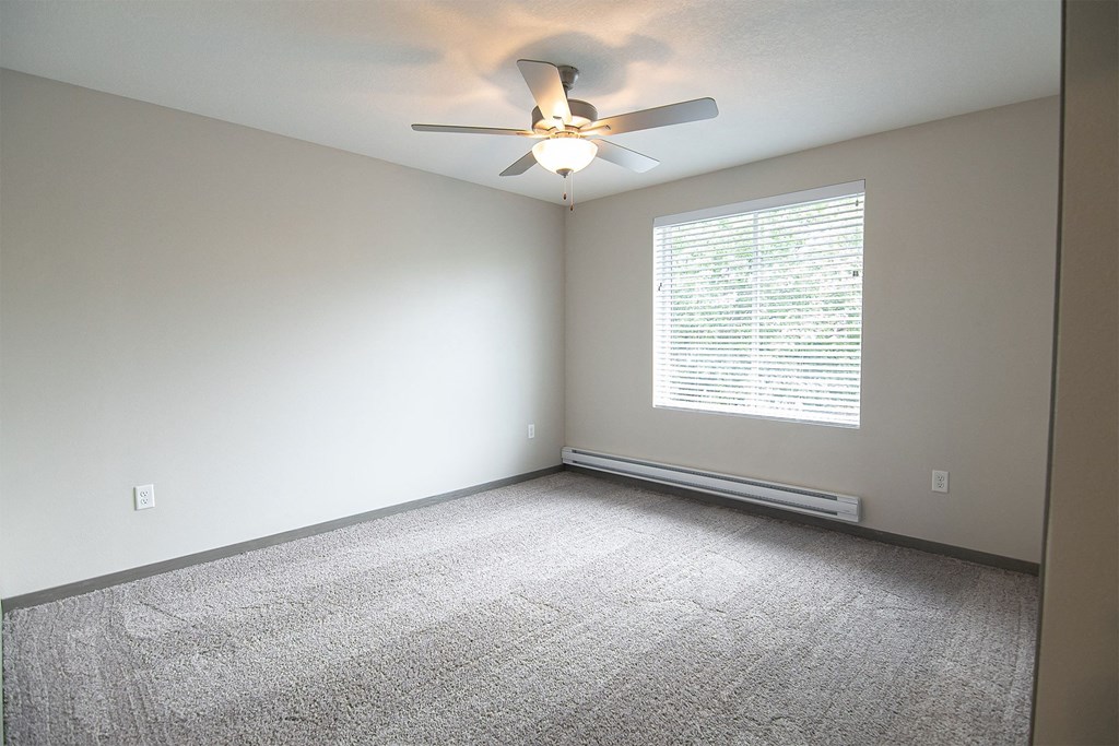 an empty room with a ceiling fan and a window