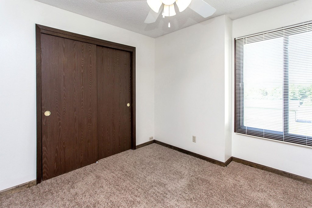 an empty bedroom with a closet and a window