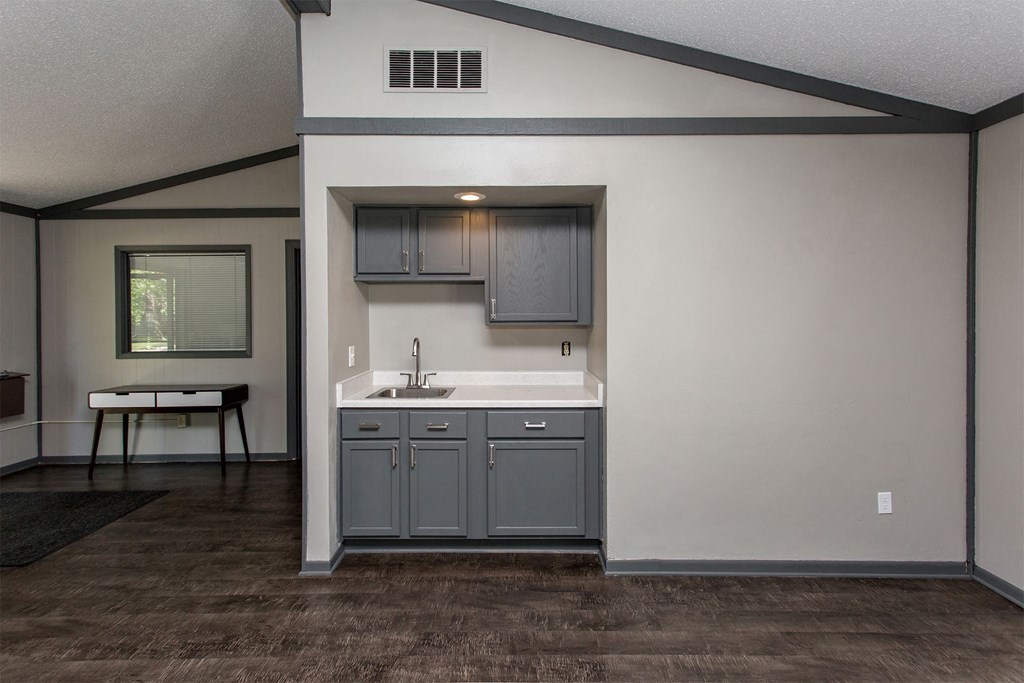 an empty living room with a sink and a kitchen
