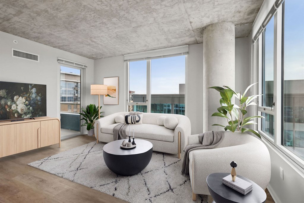 A modern living room with a white sofa, a black coffee table, and a large window.