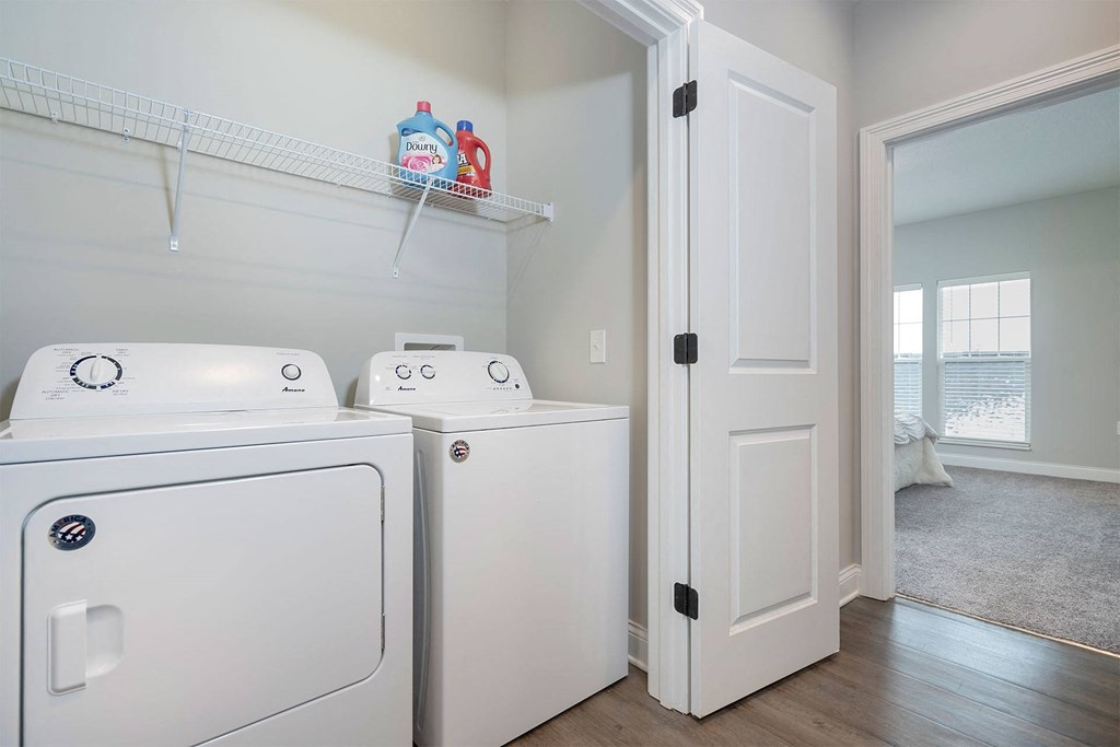 a laundry room with two washer and dryers and a door to a closet