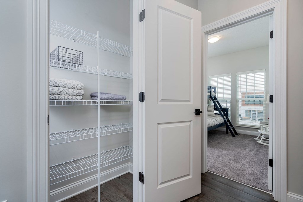 the closet of a bedroom with white closets and shelves