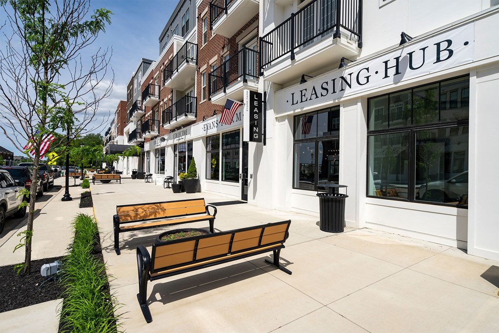 a sidewalk in front of a building with benches