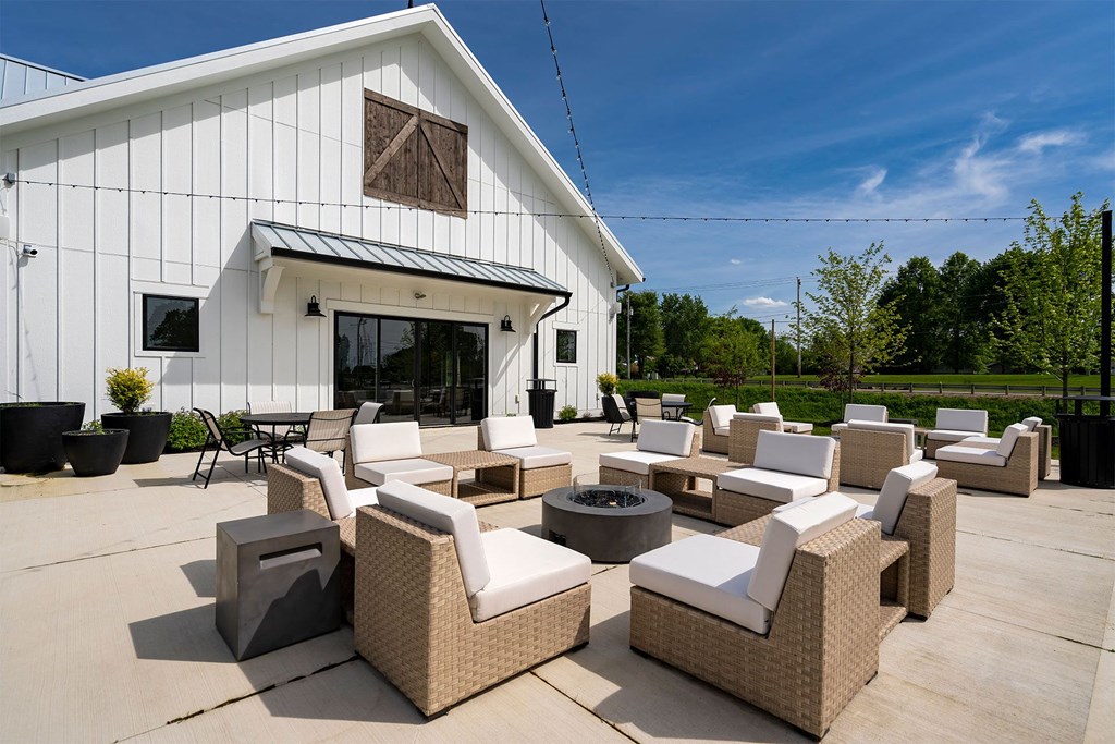 an outdoor patio with chairs and a firepit outside of a white building