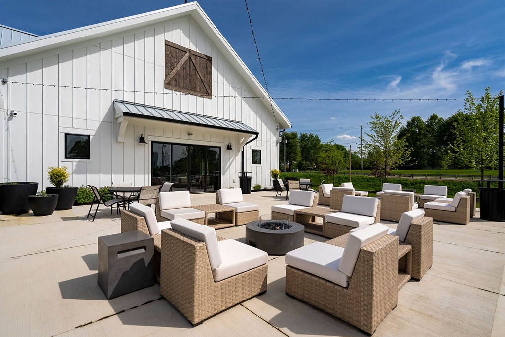 an outdoor patio with chairs and a firepit outside of a white building