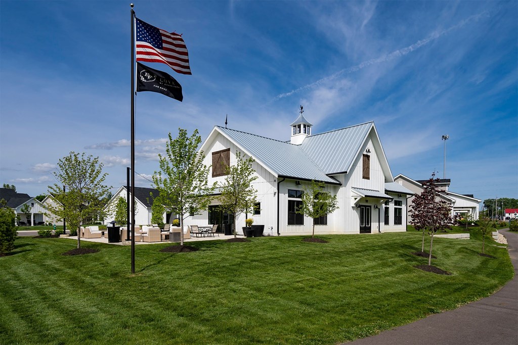 the front of a white house with an flag and a lawn