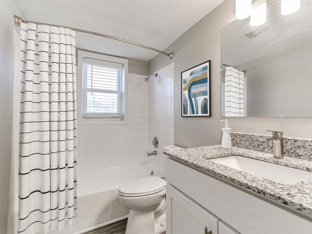 A bathroom with a toilet, sink, and shower curtain.