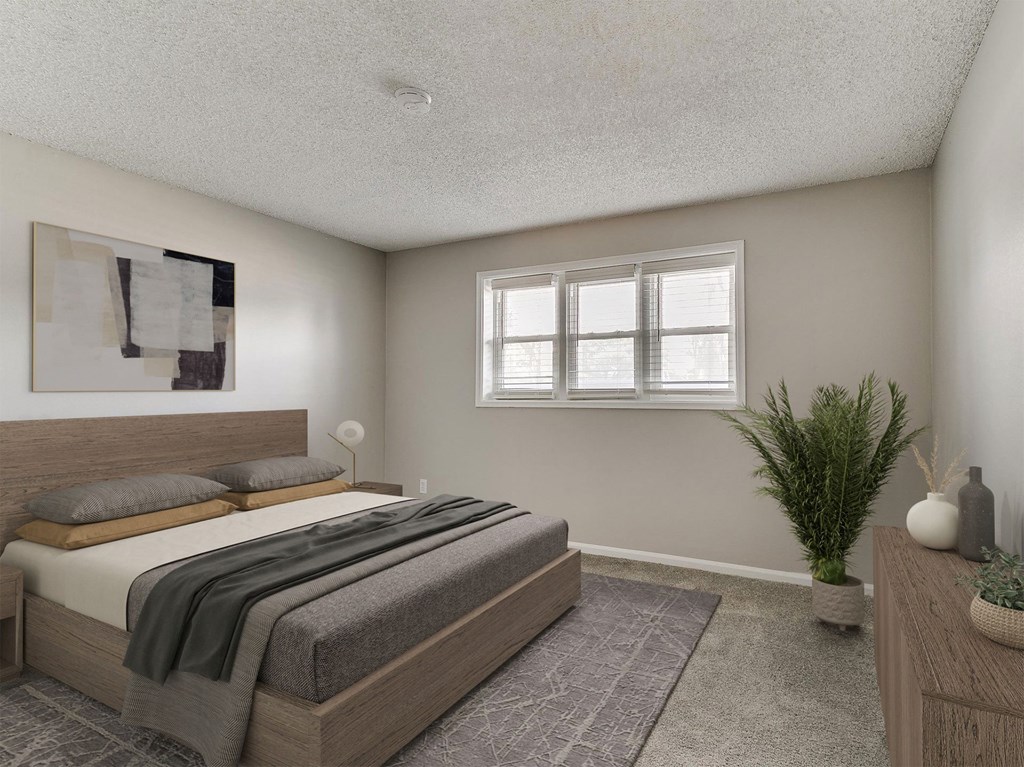 A bedroom with a large bed and a potted plant.