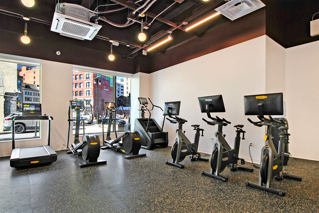 a gym with various exercise equipment on the floor and a window